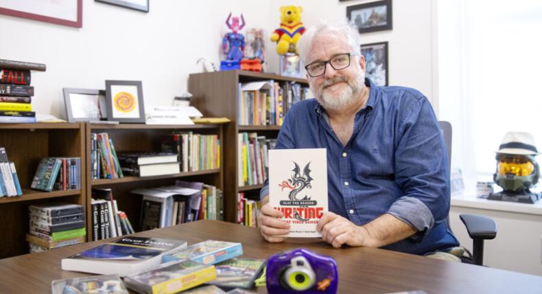 Robert Denton Bryant sits in his office holding one of the books he authored.