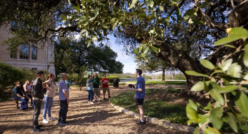 A Hilltop Hospitality student leads a campus tour and chats with guests under Sorin Oak.