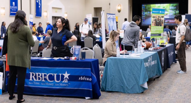 Students interact with employers tabling at a job fair.