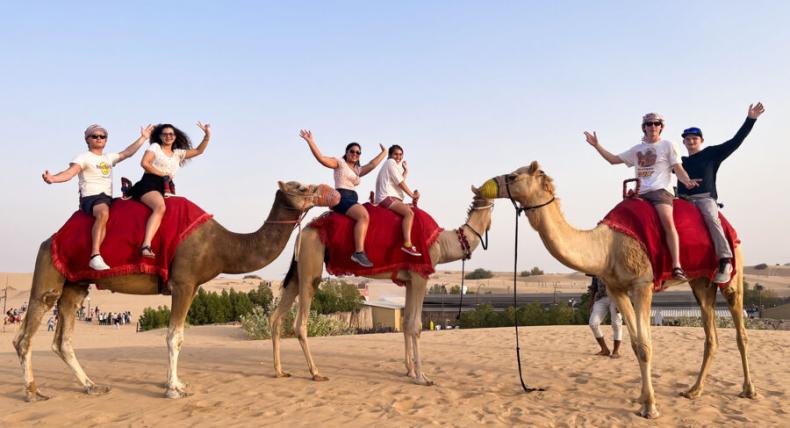 Six students ride three camels on a study abroad trip.