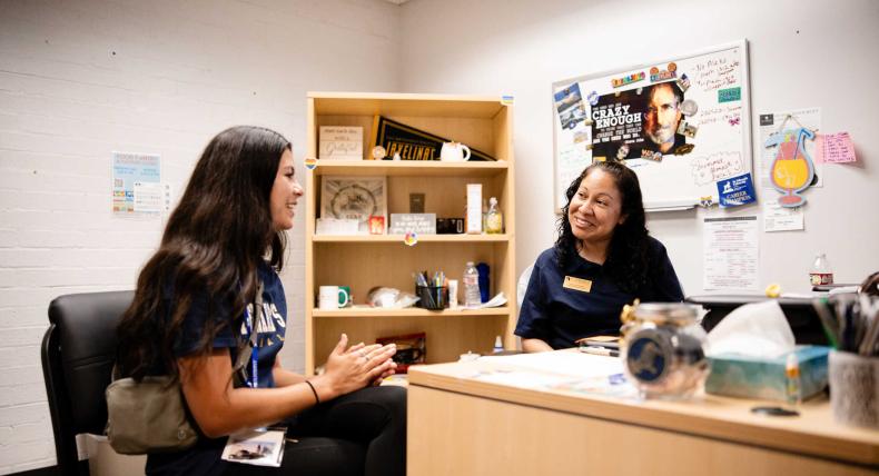 Success coach advises student in university office.