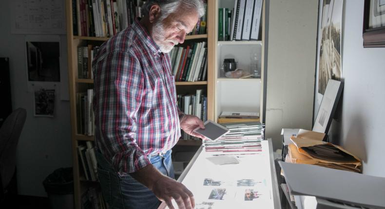 Professor Bill Kennedy looks at photography negatives on a lightboard in his office.