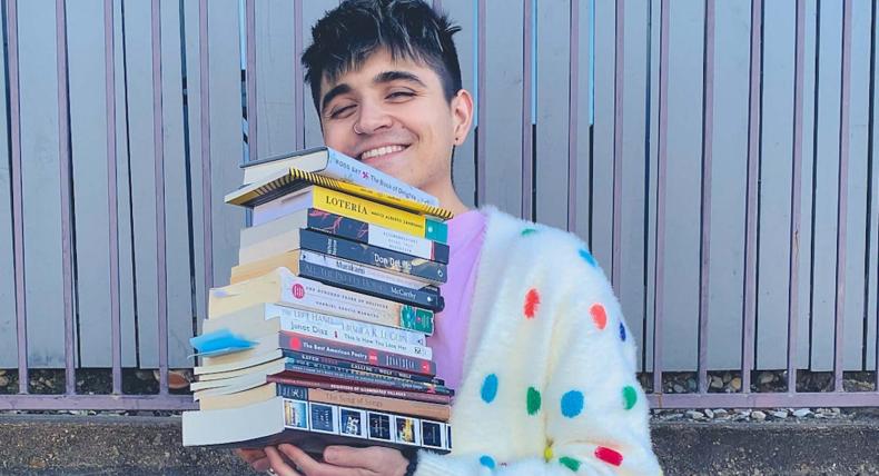 Quinn Gavin holds a stack of his favorite books in fun colorful polkadot sweater