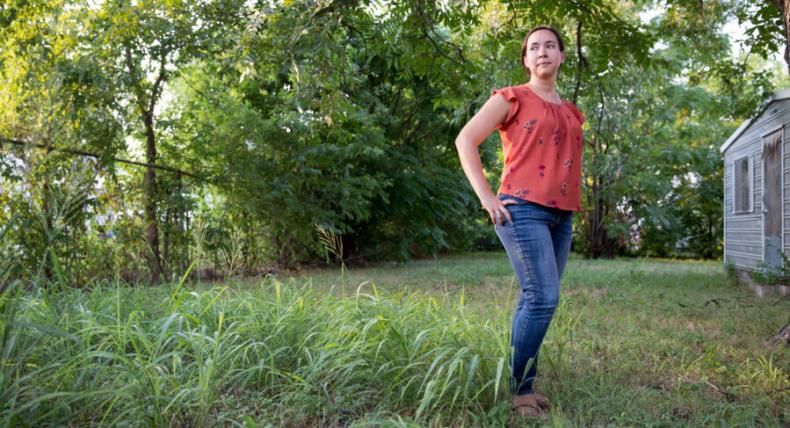 Victoria Rodriguez stands in a green yard with trees behind her. 