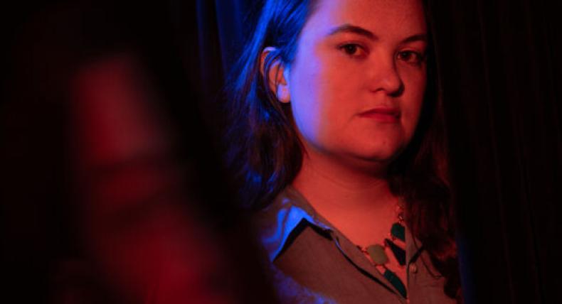 Kit Taylor is illuminated by red and blue lights for a portrait.