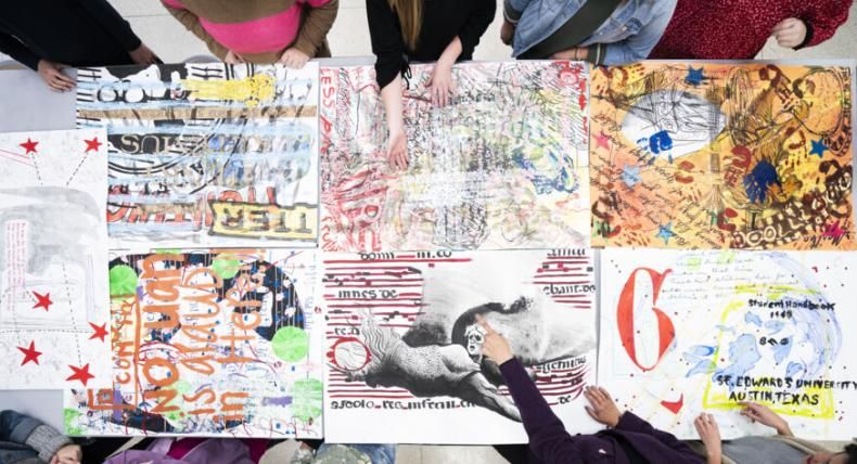 An overhead view of a class looking at and pointing at pieces of artwork.