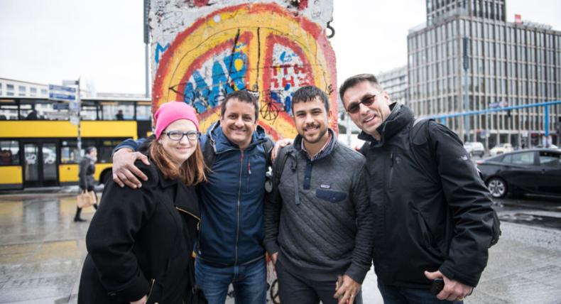 Four graduate students stand in front of a piece of the Berlin Wall in Berlin.