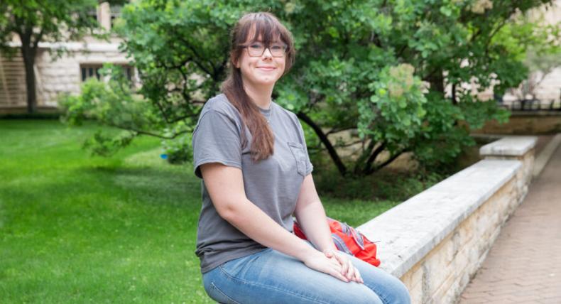 Audrey Alexander sits near the Ragsdale Patio area with greenery behind her.