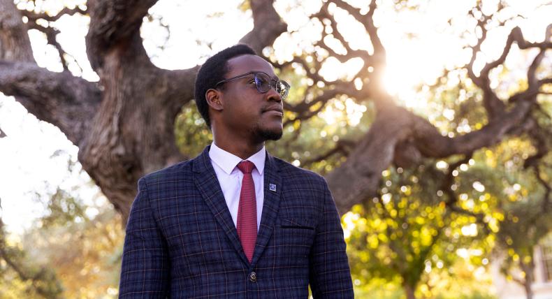 Student, Emmanuel Epau, poses in front of Sorin Oak