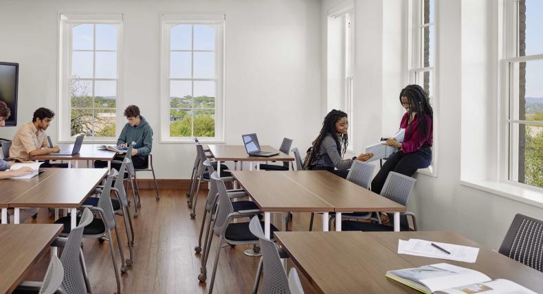 Four students sit around a classroom engaged in conversation in Holy Cross Hall.