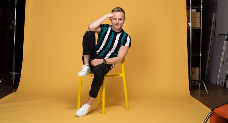 Tyler Mount sits in a yellow chair on a yellow background.