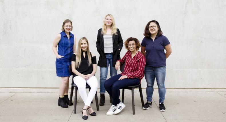 5 of the 6 winners of the Fulbright Award sit and stand for a portrait outside of Munday Library.