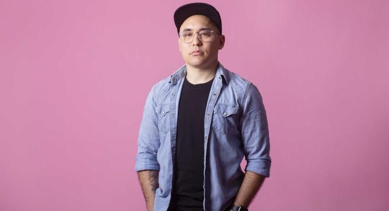 Jake Nishimura stands in font of a pink backdrop for a portrait.