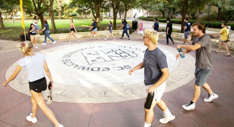 several students walking around the campus seal as apart of the legacy walk ceremony 