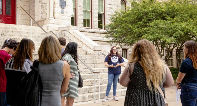 Campus Tour Guide speaks to visitors in front of Main Building