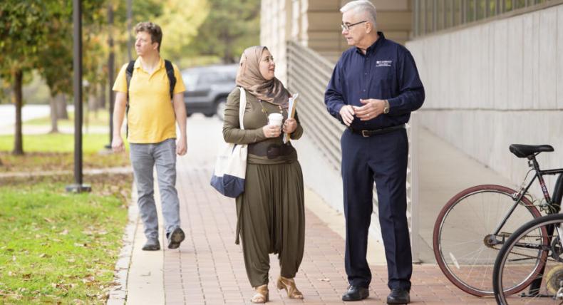 student and professor walking and talking outdoors on campus 