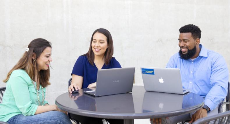 3 students studying with two laptops at a table