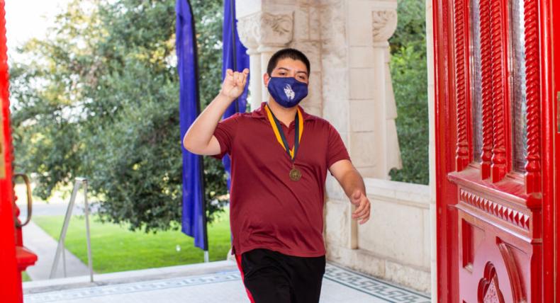 student with blue COVID mask walking on campus 