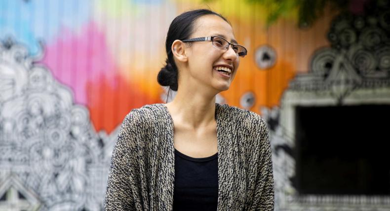 Murphy Chen stands in front of a colorful mural in downtown Austin.