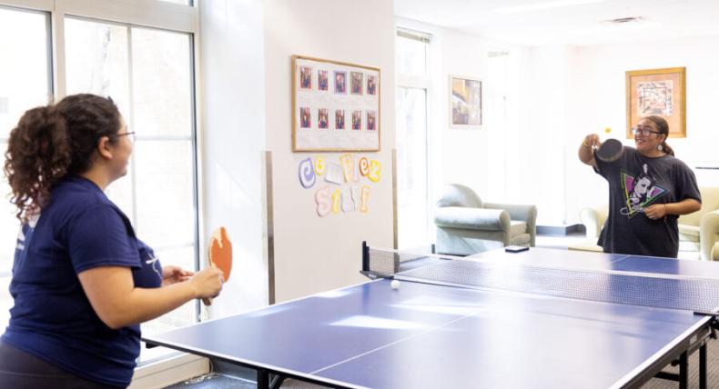 2 students playing ping pong in a residence hall 