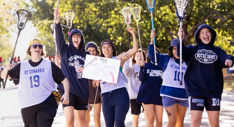 Members of the women's lacrosse club sports team march in the homecoming parade.