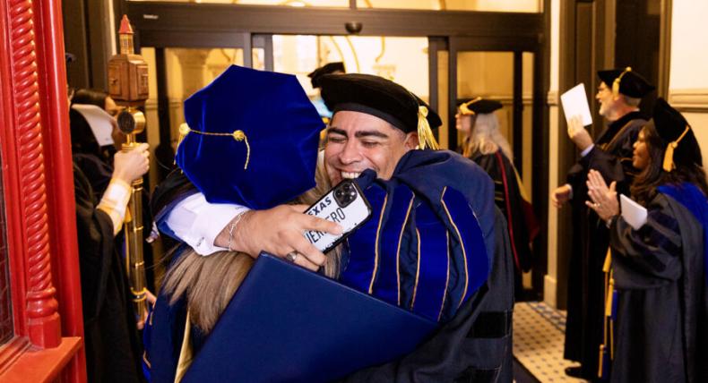 student hugging the president at graduation 