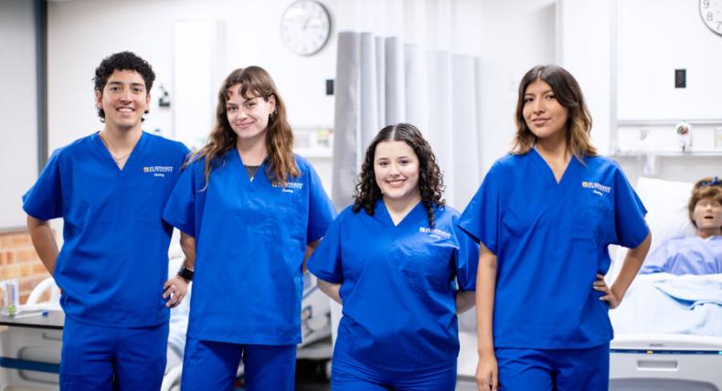 4 nursing students in blue scrubs 