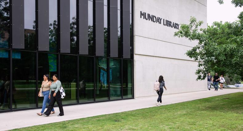 Students walk on a path outside of the Munday Library.