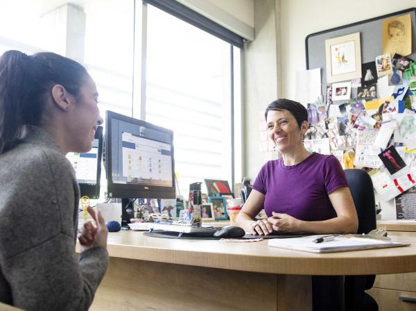 Staff member advises student in university office.