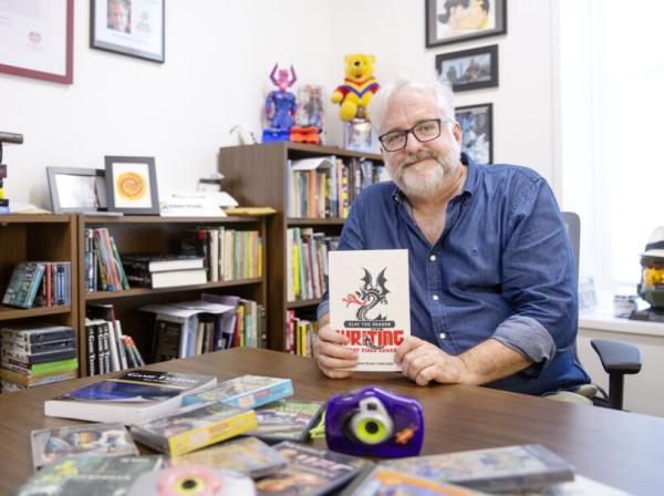 Robert Denton Bryant sits in his office holding one of the books he authored.