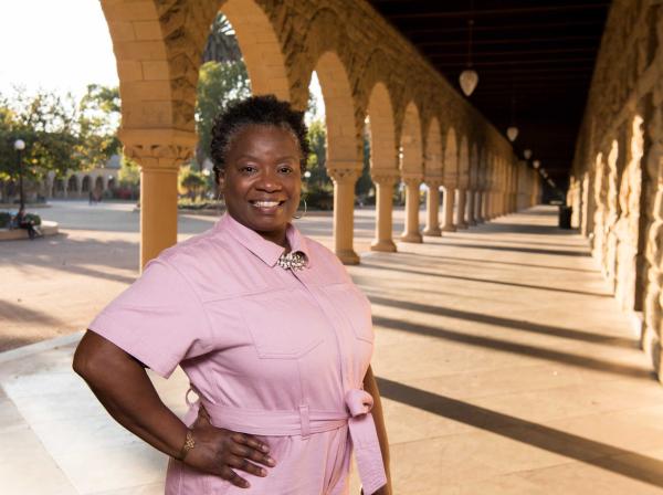 Mona Hick stands in a pink jumpsuit on Stanford's campus.