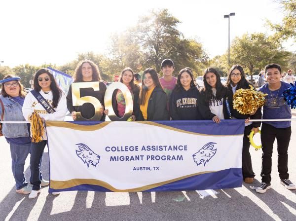 Students holding a College Assistance Migrants Program banner at a parade 