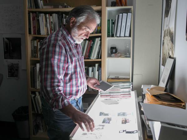 Professor Bill Kennedy looks at photography negatives on a lightboard in his office.