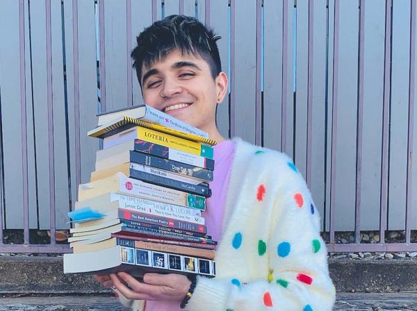 Quinn Gavin holds a stack of his favorite books in fun colorful polkadot sweater