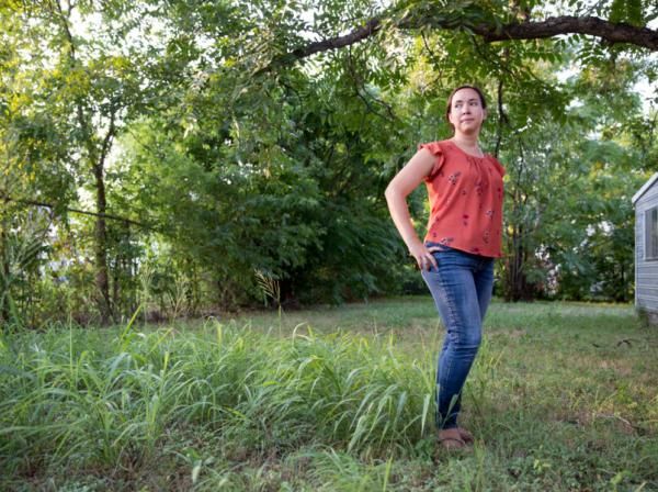 Victoria Rodriguez stands in a green yard with trees behind her. 