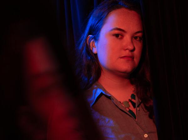 Kit Taylor is illuminated by red and blue lights for a portrait.