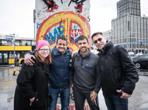 Four graduate students stand in front of a piece of the Berlin Wall in Berlin.