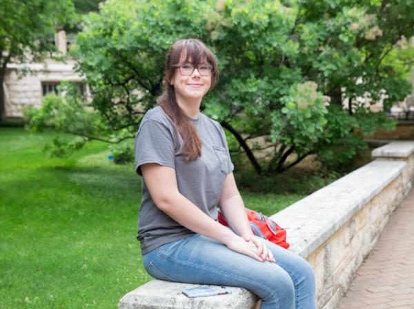 Audrey Alexander sits near the Ragsdale Patio area with greenery behind her.