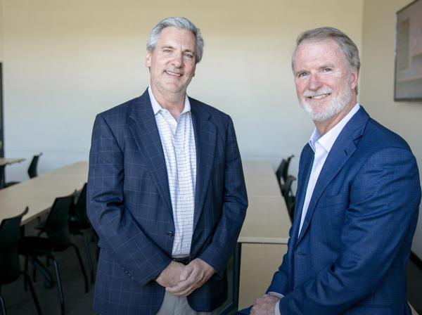 Alumni Steve Shadowen and Bob Hilliard wear blazers and are in a classroom in the Munday Library.