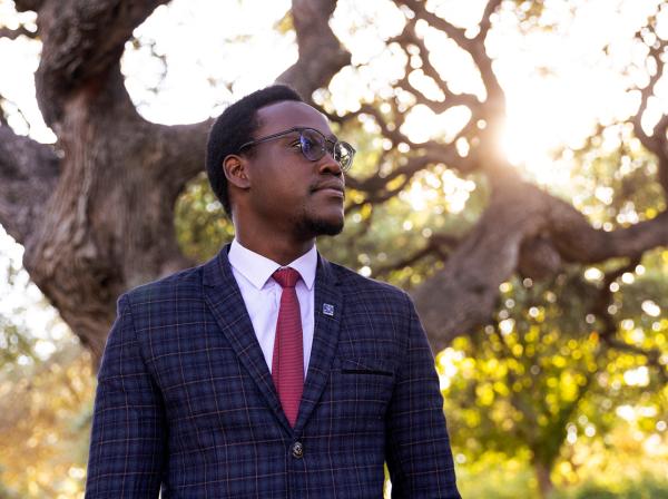 Student, Emmanuel Epau, poses in front of Sorin Oak