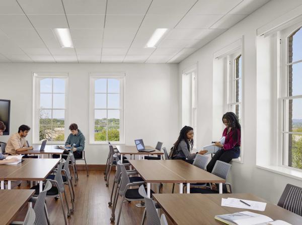 Four students sit around a classroom engaged in conversation in Holy Cross Hall.