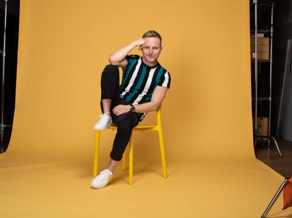 Tyler Mount sits in a yellow chair on a yellow background.