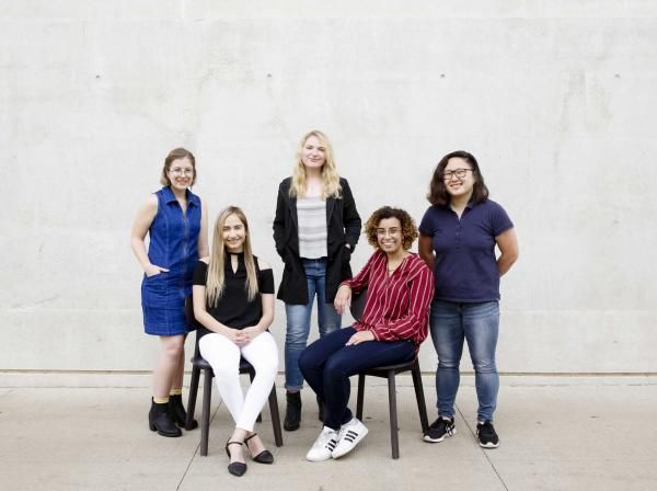 5 of the 6 winners of the Fulbright Award sit and stand for a portrait outside of Munday Library.