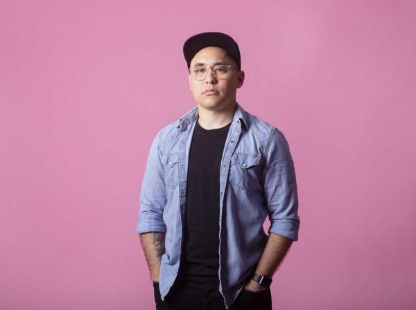 Jake Nishimura stands in font of a pink backdrop for a portrait.