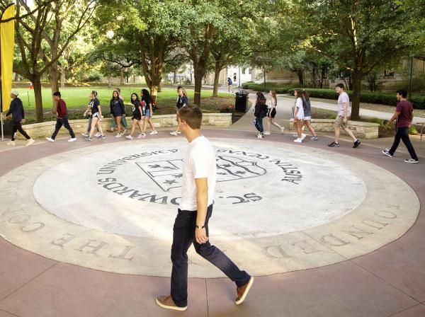 Students walk around the university seal during the Legacy Walk.