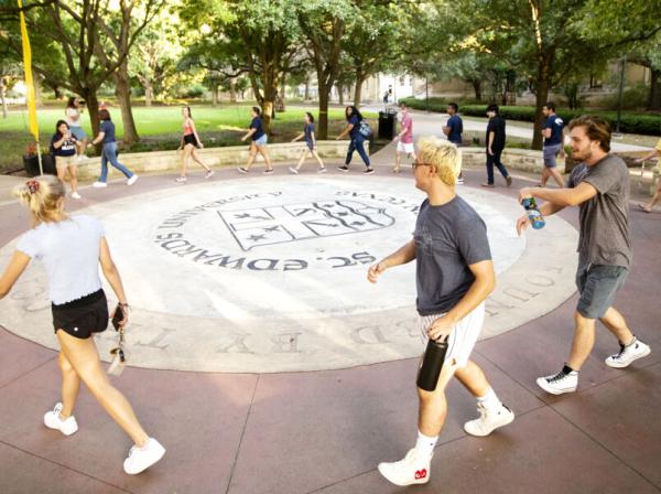 several students walking around the campus seal as apart of the legacy walk ceremony 