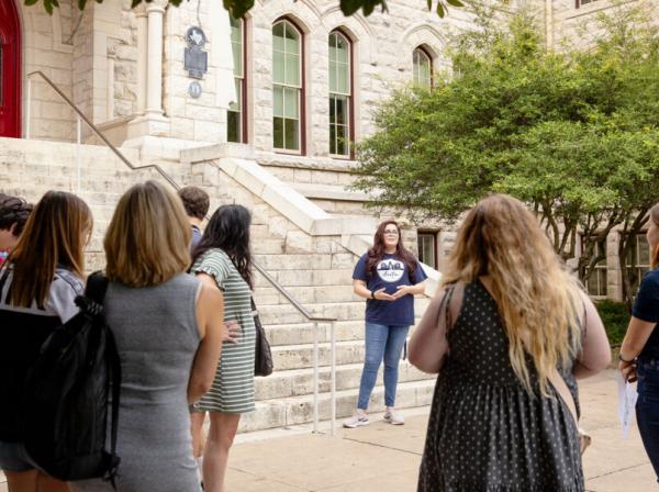 Campus Tour Guide speaks to visitors in front of Main Building