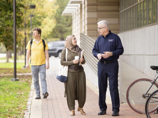 student and professor walking and talking outdoors on campus 