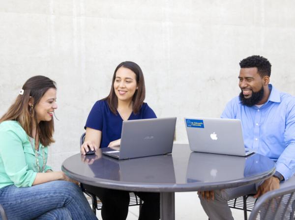 3 students studying with two laptops at a table