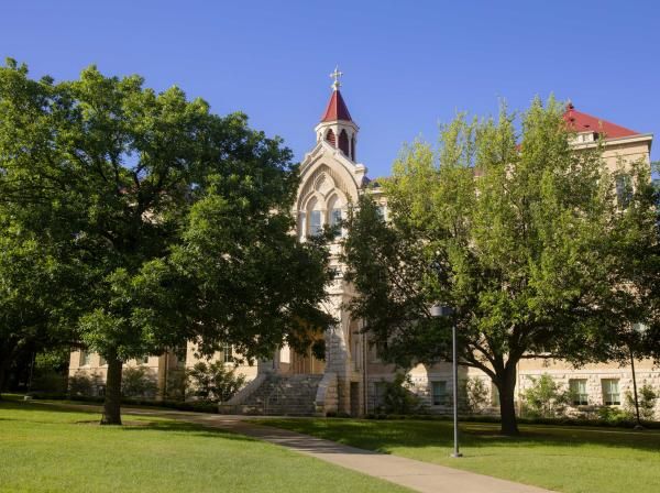 Holy Cross Hall framed by green trees on a sunny day.